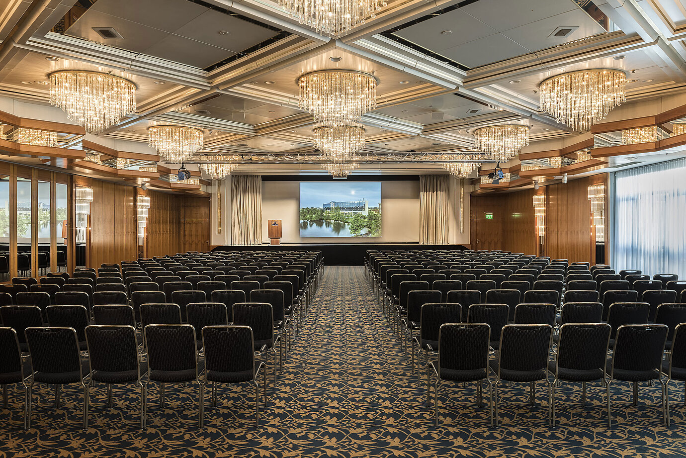 Eleganter Veranstaltungssaal mit Kristalllüstern, Reihenbestuhlung und großer Bühne im Maritim Hotel Hannover.