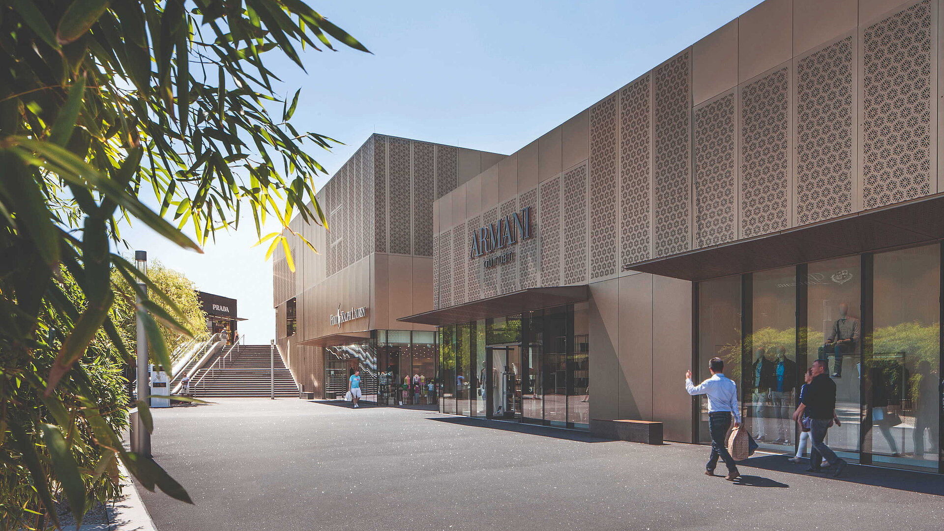 Shopping Armani Outlet Store mit moderner Fassade, Einkaufsbereich und Besuchern bei Sonnenschein