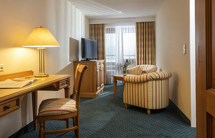 Wohnbereich mit TV, Schreibtisch und bequemen Sesseln im Maritim Hotel Titisee