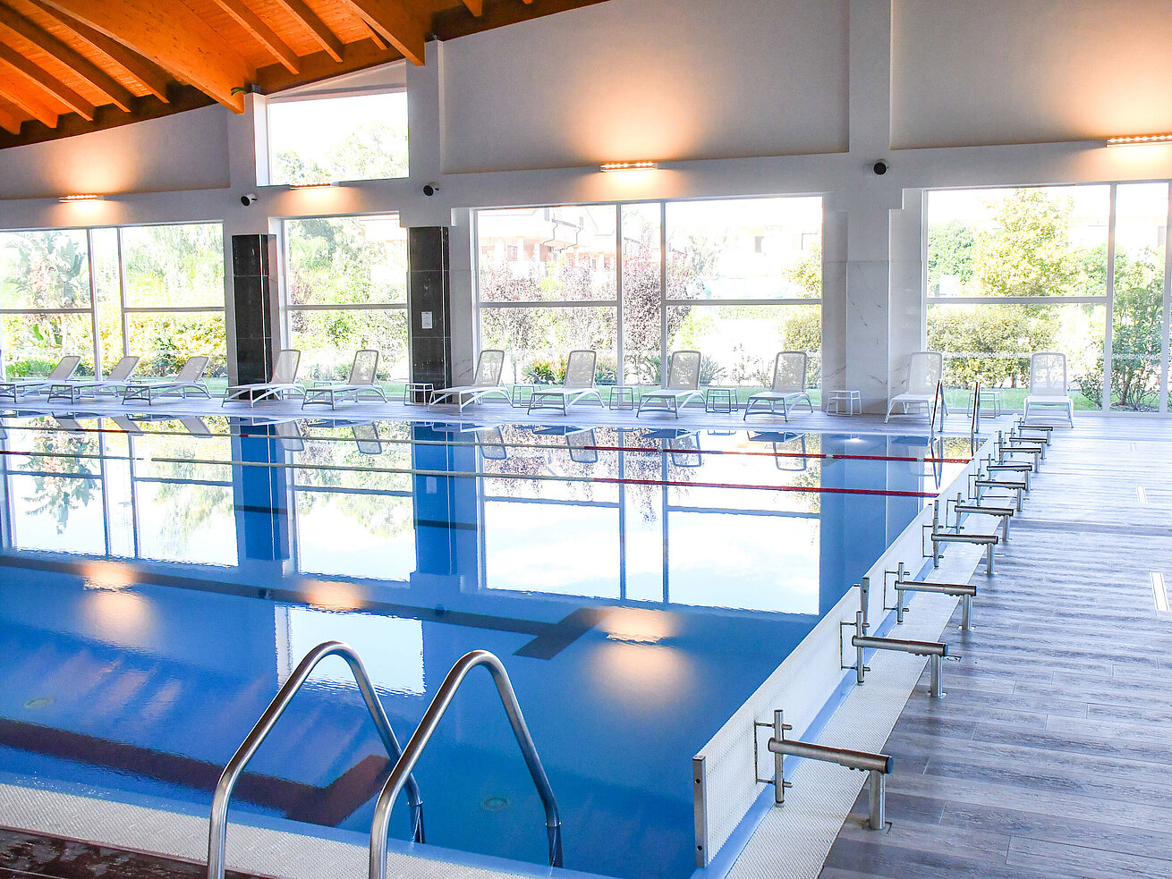 Hallenbad Modernes Hallenbad mit großen Fenstern und Liegestühlen im Resort