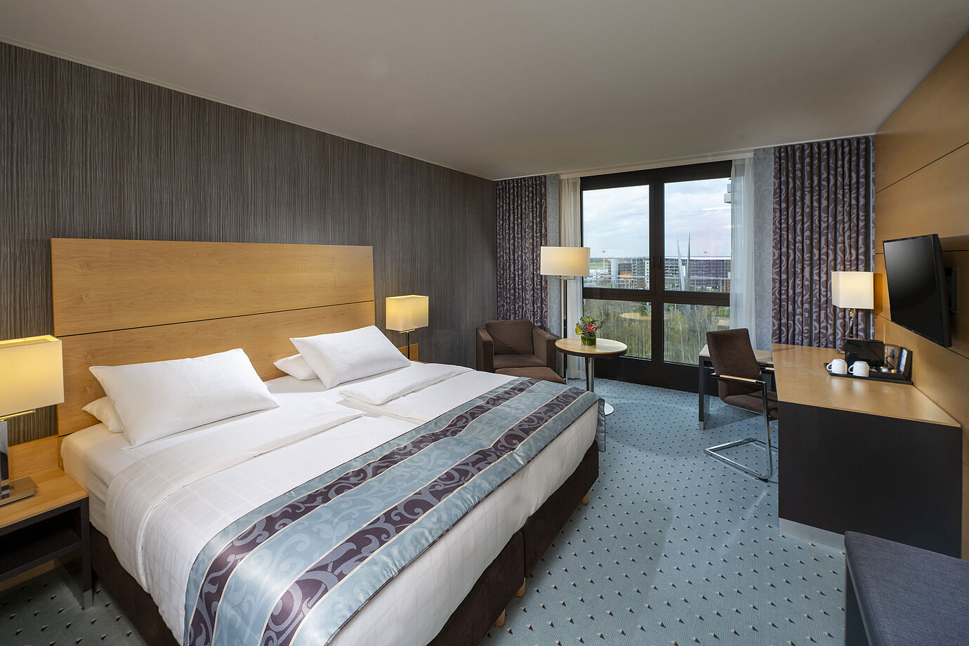 Modernes Superior-Zimmer im Maritim Hotel Düsseldorf mit großem Bett, Schreibtisch und Blick auf die Stadt.
