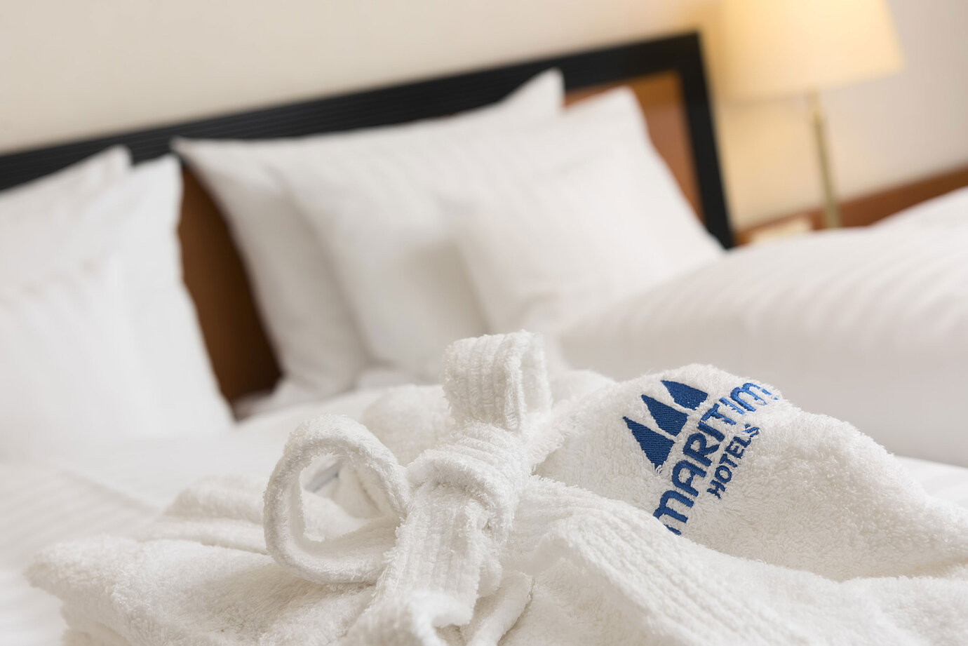 Weicher Bademantel mit Maritim-Logo auf dem Bett im Maritim Hotel Bad Salzuflen