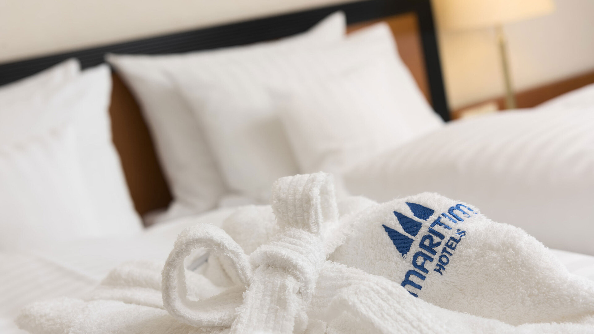 Weicher Bademantel mit Maritim-Logo auf dem Bett im Maritim Hotel Bad Salzuflen