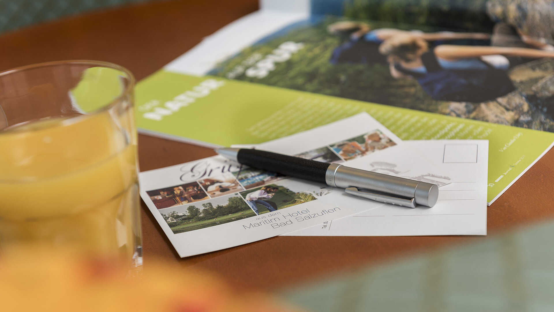 Tisch mit Postkarte vom Maritim Hotel Bad Salzuflen, Kugelschreiber, Saft und Broschüre