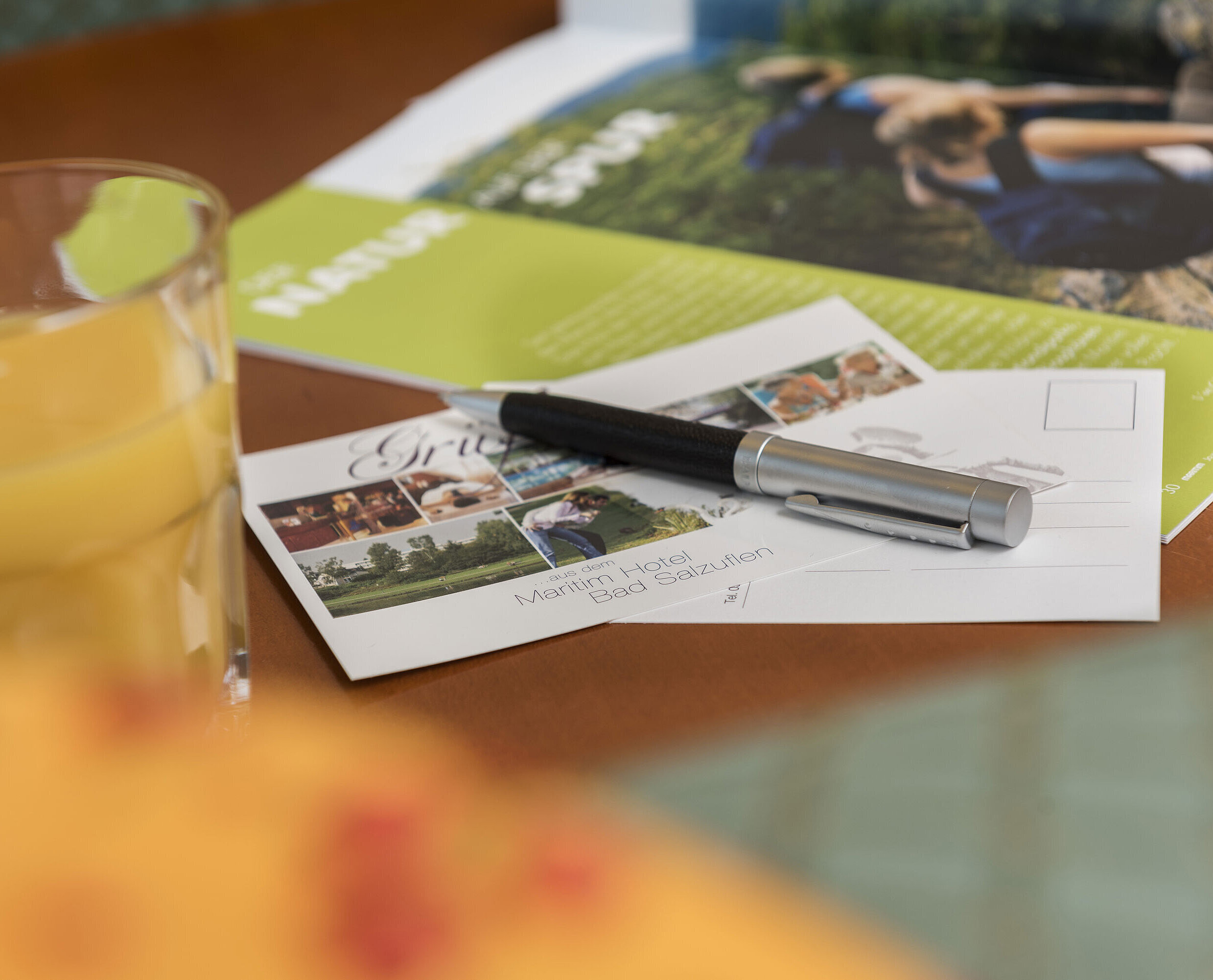 Tisch mit Postkarte vom Maritim Hotel Bad Salzuflen, Kugelschreiber, Saft und Broschüre