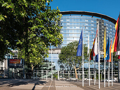 Außenansicht des Congress Center Messe Frankfurt mit Glasfassade und Flaggen vor dem Gebäude.