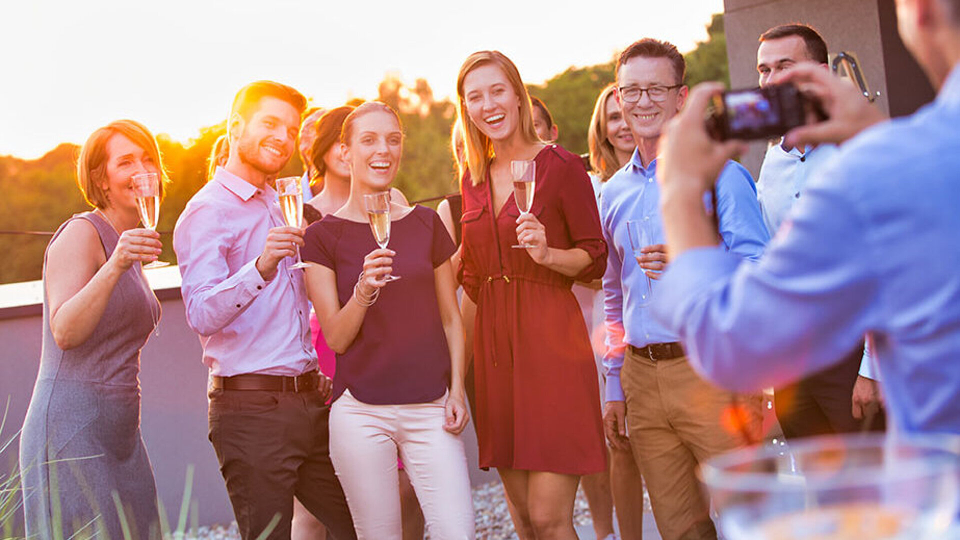 © moodboard - AdobeStock.com Gruppe von Gästen posiert gemeinsam für ein Foto bei einer Feier im Freien