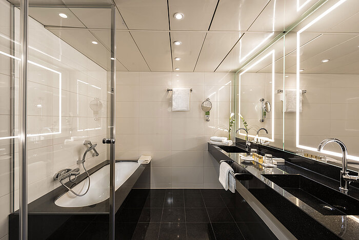 Geräumiges Suite-Badezimmer mit moderner Badewanne, Doppelwaschbecken und eleganter Beleuchtung im Maritim Hotel Bonn.