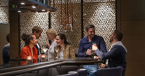 Gäste genießen Drinks und gesellige Gespräche in der stilvollen Bar des Maritim Hotel Ingolstadt.