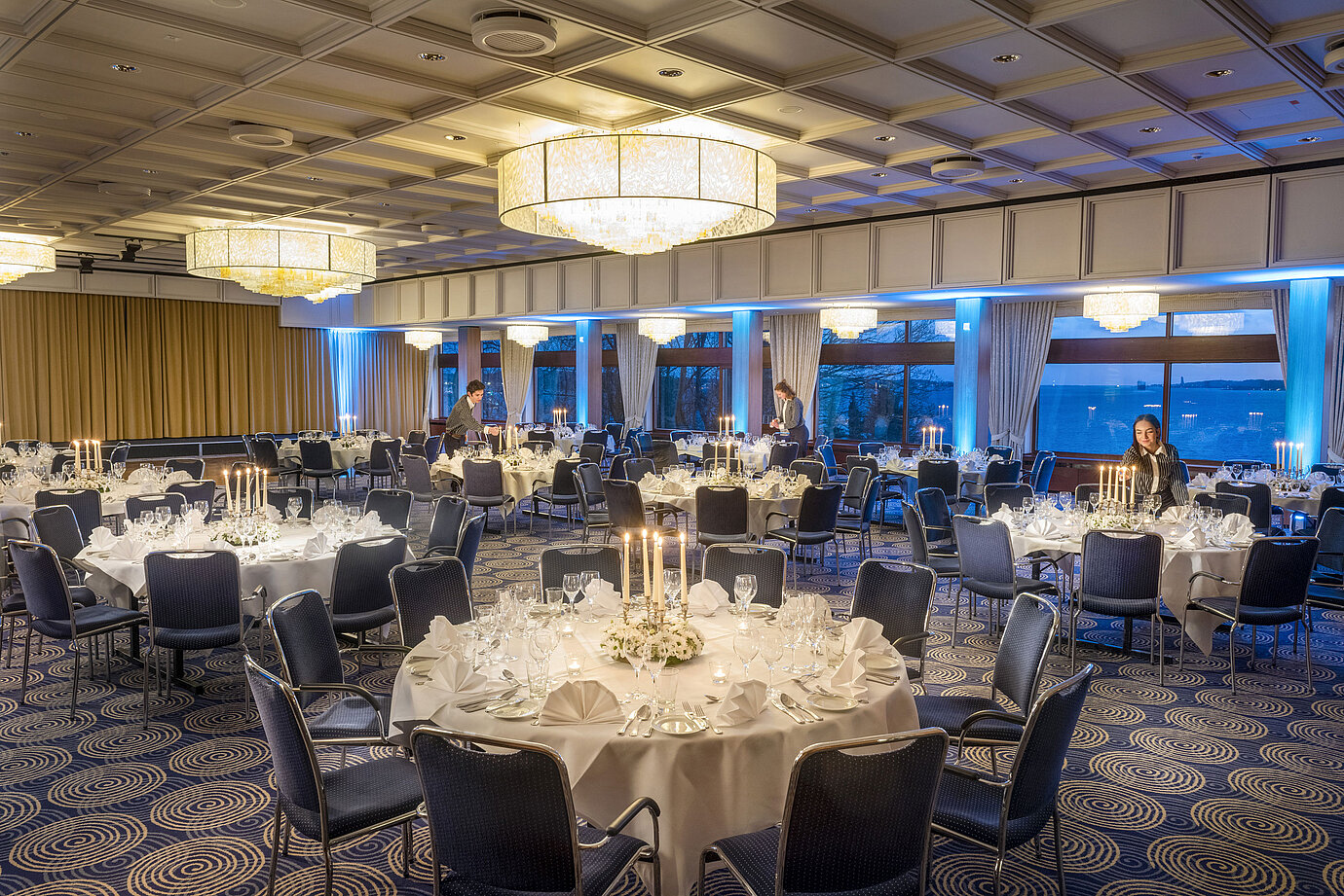 Saal Maritim im Maritim Hotel Kiel, festlich gedeckte Tische mit Kerzenlicht, elegantes Ambiente, Personal bereitet die Veranstaltung vor.