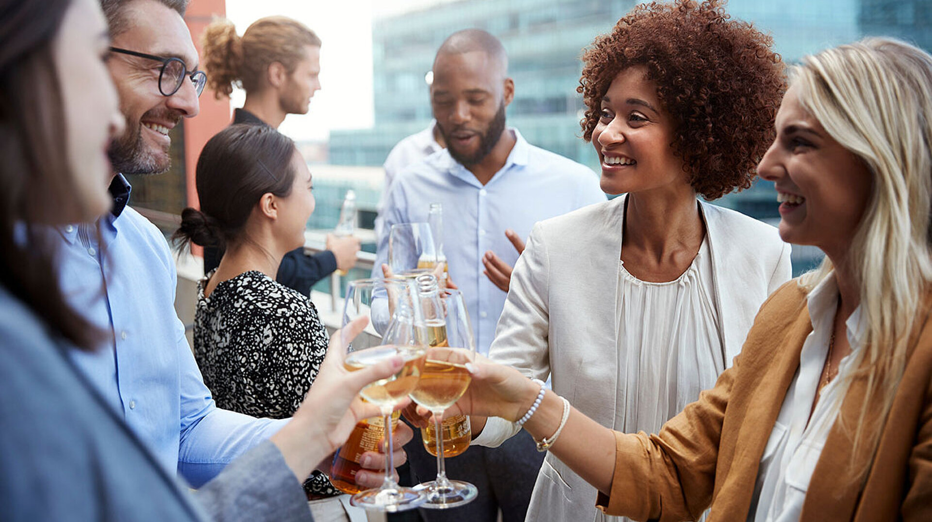 Kolleg:innen stoßen bei einem Business-Event mit Getränken an und genießen den gemeinsamen Austausch.