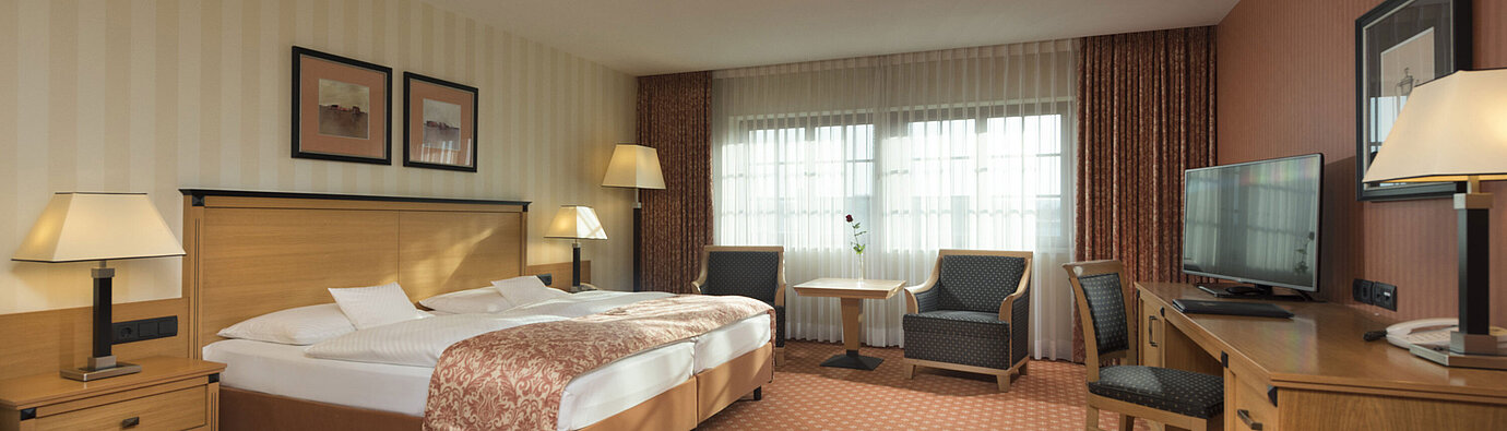 Classic Zimmer im Maritim Hotel Dresden mit Doppelbett, Sitzbereich und klassischem Dekor.