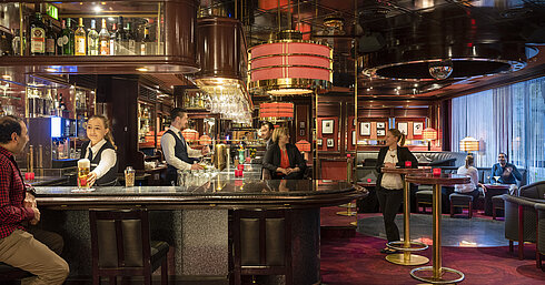 Gäste genießen Drinks und entspannte Atmosphäre in der stilvollen Bar des Maritim Bremen, bedient von freundlichem Personal.