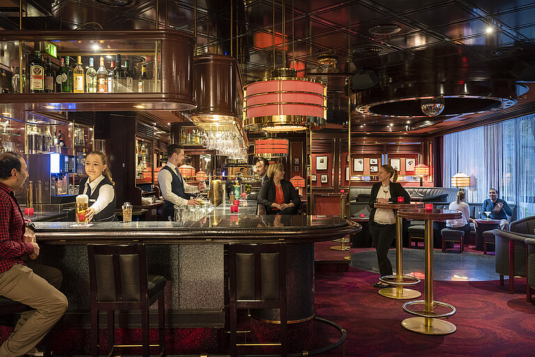 Gäste genießen Drinks und entspannte Atmosphäre in der stilvollen Bar des Maritim Bremen, bedient von freundlichem Personal.