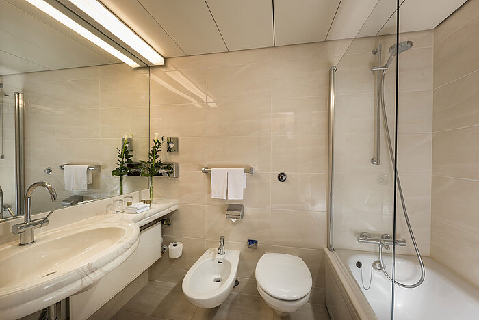 Modernes Badezimmer mit Badewanne, Dusche, Bidet und großem Spiegel im Maritim Hotel Hannover.