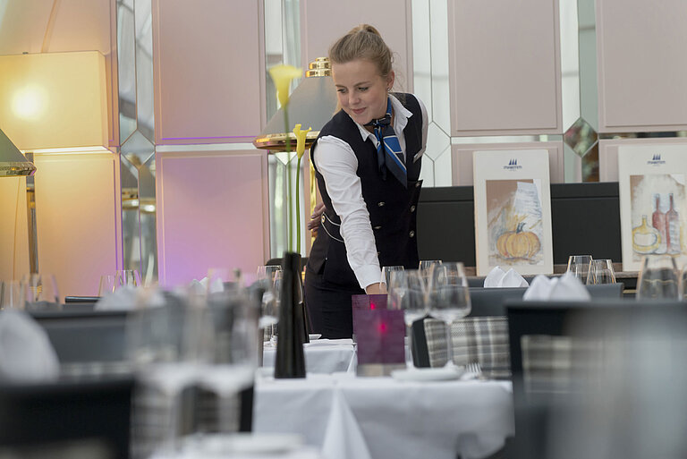 Servicekraft deckt stilvoll den Tisch im Restaurant des Maritim Hotel München