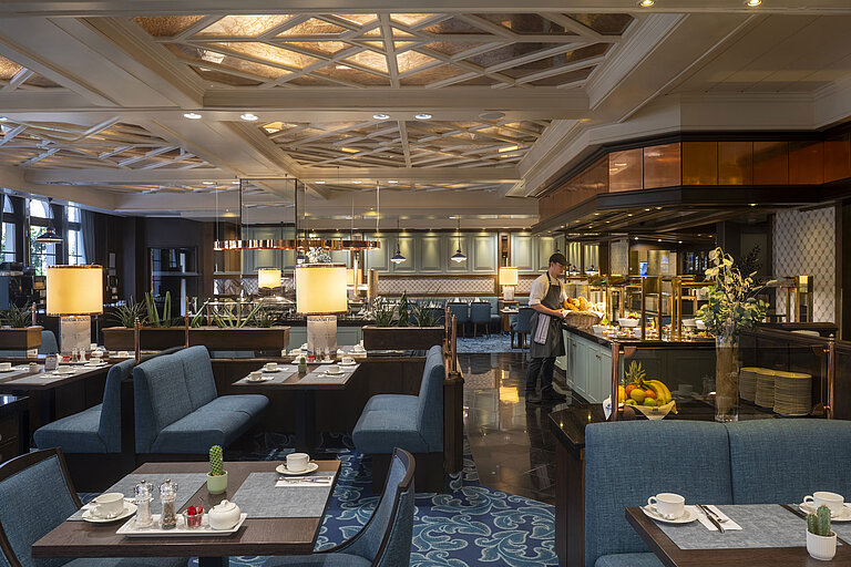 Restaurant im Maritim Hotel Darmstadt mit gedeckten Tischen, Buffetbereich und eleganter Beleuchtung unter kunstvoller Decke.