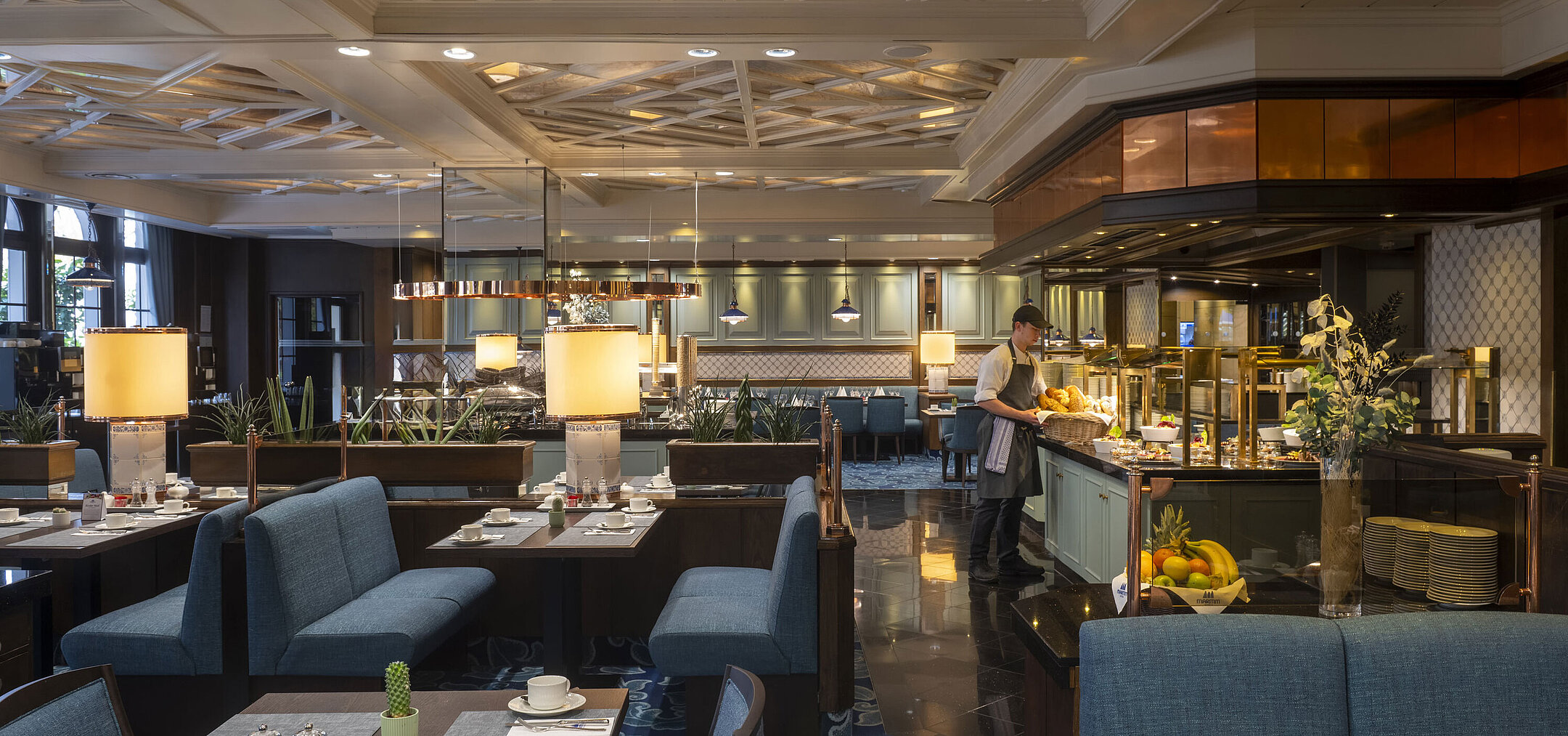 Restaurant im Maritim Hotel Darmstadt mit gedeckten Tischen, Buffetbereich und eleganter Beleuchtung unter kunstvoller Decke.