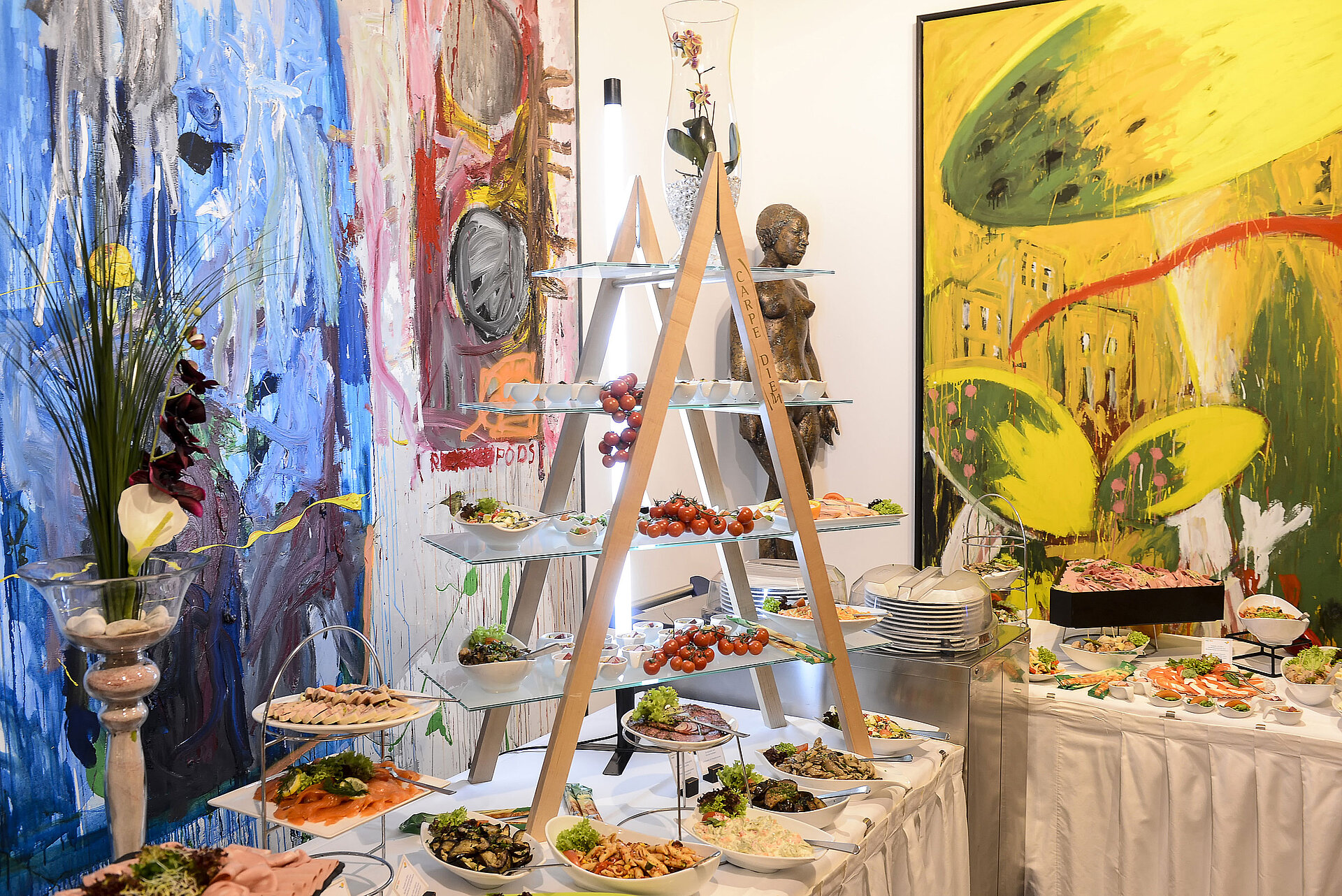 Buffet | Maritim proArte Hotel Berlin Kunstvoll gestaltetes Buffet im Maritim proArte Hotel Berlin mit einer Auswahl an Speisen vor bunten Gemälden.