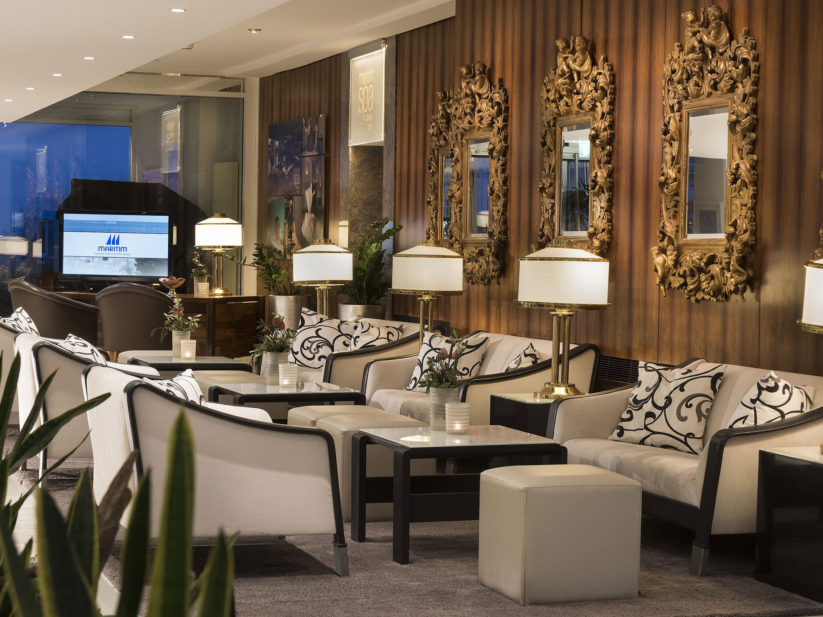 Elegante Lobby mit Sitzgelegenheiten und goldenen Spiegeln im Maritim Seehotel Timmendorfer Strand.