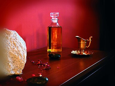 Stimmungsvolle Nahaufnahme mit Flasche Massageöl, Stein und Kupferdeko im Maritim Hotel Bad Wildungen
