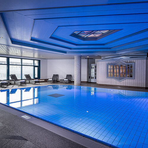 Innenpool im Maritim Hotel Hannover mit Liegestühlen und moderner Beleuchtung.