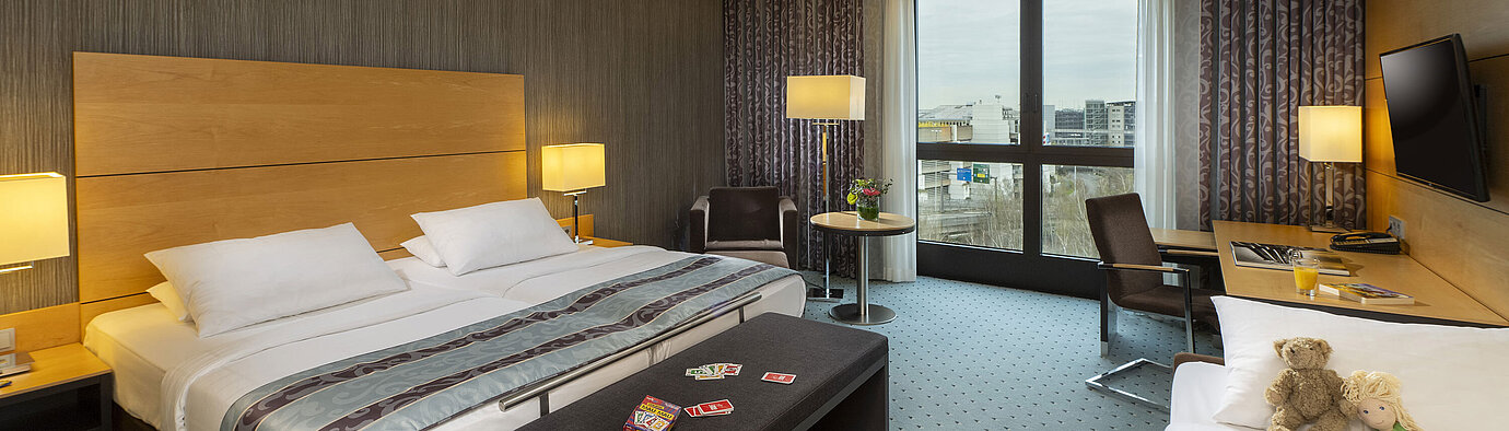 Classic Familienzimmer im Maritim Hotel Düsseldorf mit großem Doppelbett, Einzelbett, Spielkarten und Plüschtieren für Kinder
