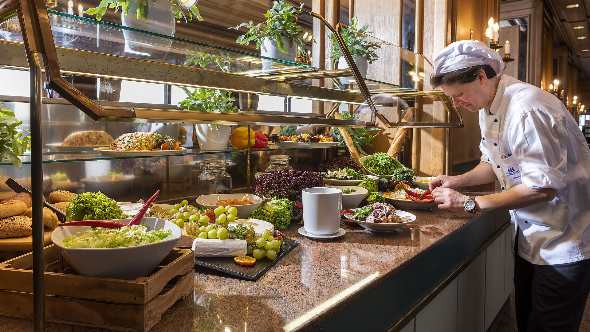 Küchenchef bereitet frisches Salat- und Gemüsebuffet im Restaurant des Maritim Hotel Travemünde vor