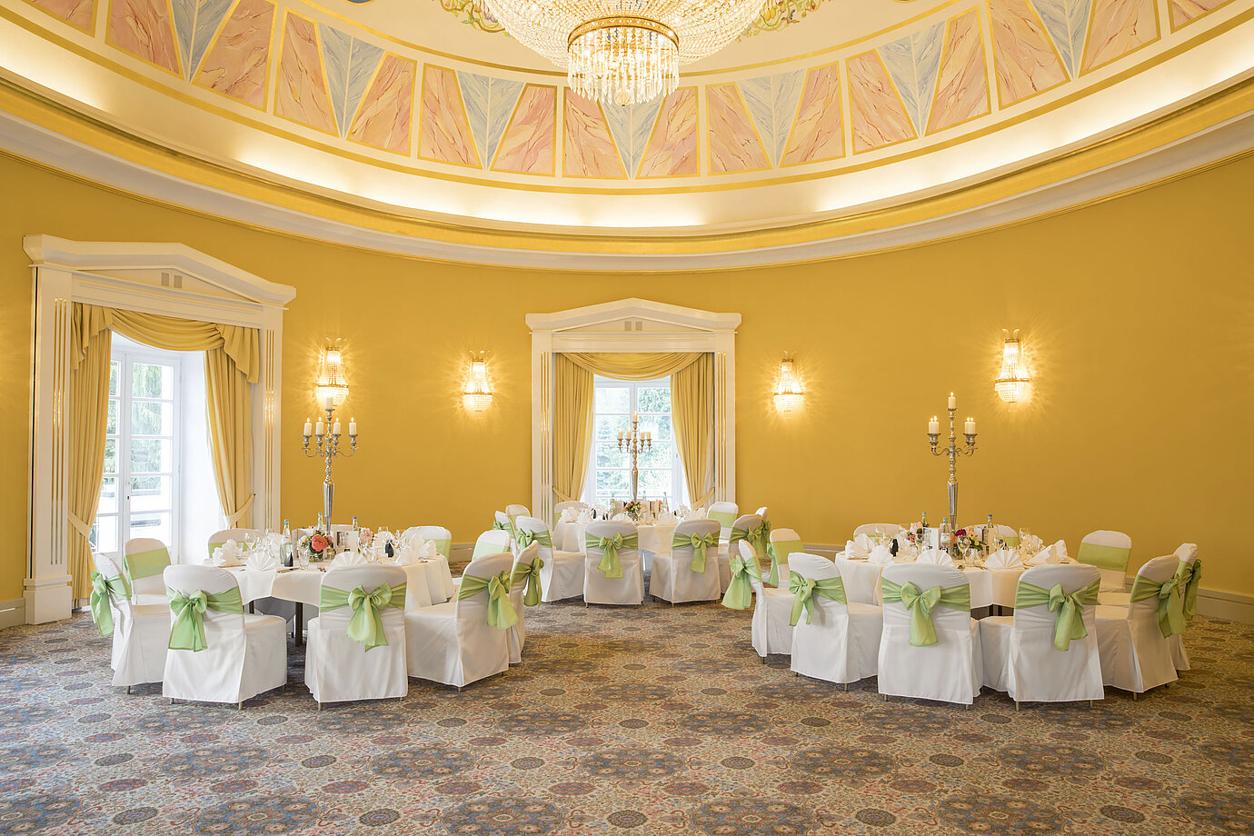 Eleganter Festsaal mit gelben Wänden, runden Tischen und Kerzenhaltern im Maritim Hotel Bad Wildungen