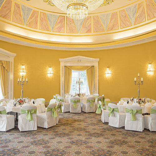 Eleganter Festsaal mit gelben Wänden, runden Tischen und Kerzenhaltern im Maritim Hotel Bad Wildungen