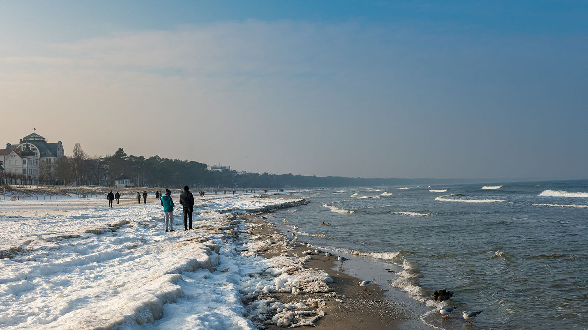 © spuno - AdobeStock.com Ostseeküste mit Wellen, Strand und Blick auf die Küstenlandschaft bei blauem Himmel