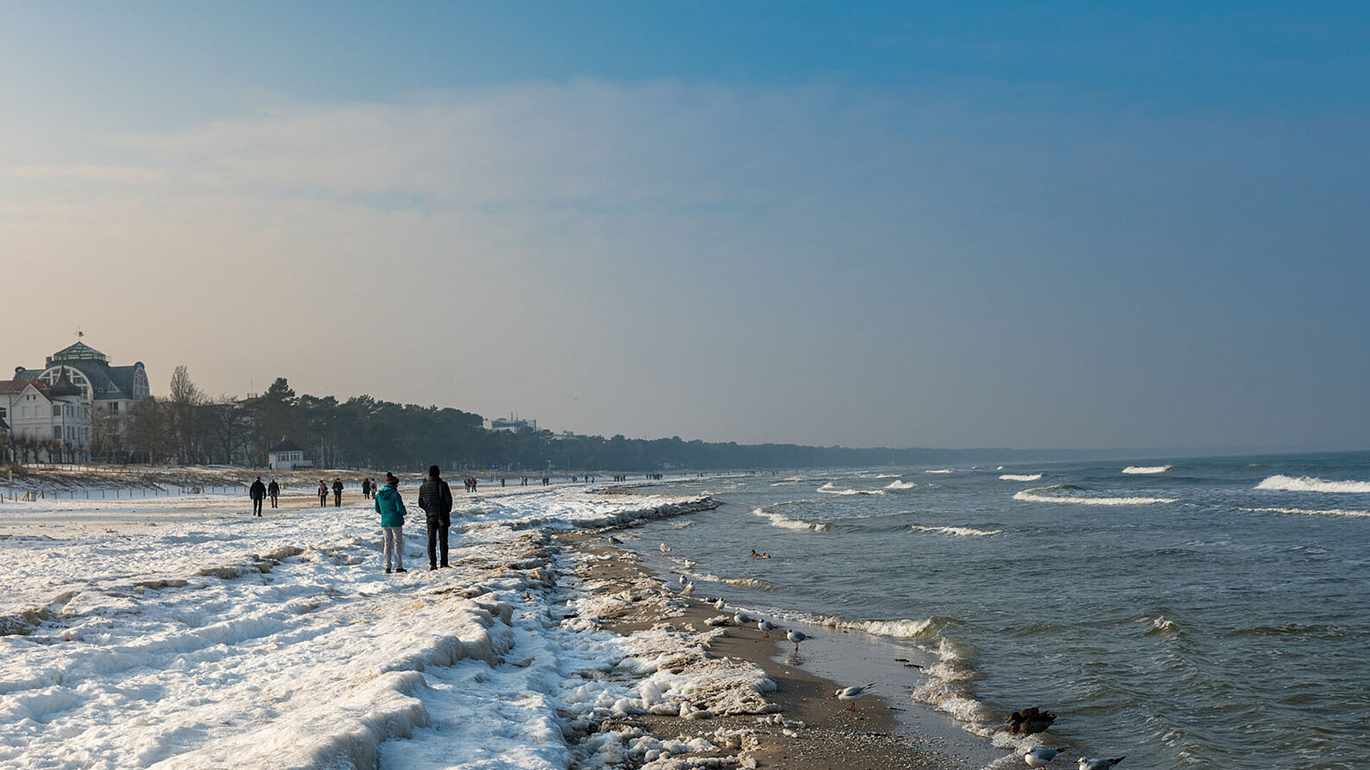 Ostseeküste mit Wellen, Strand und Blick auf die Küstenlandschaft bei blauem Himmel