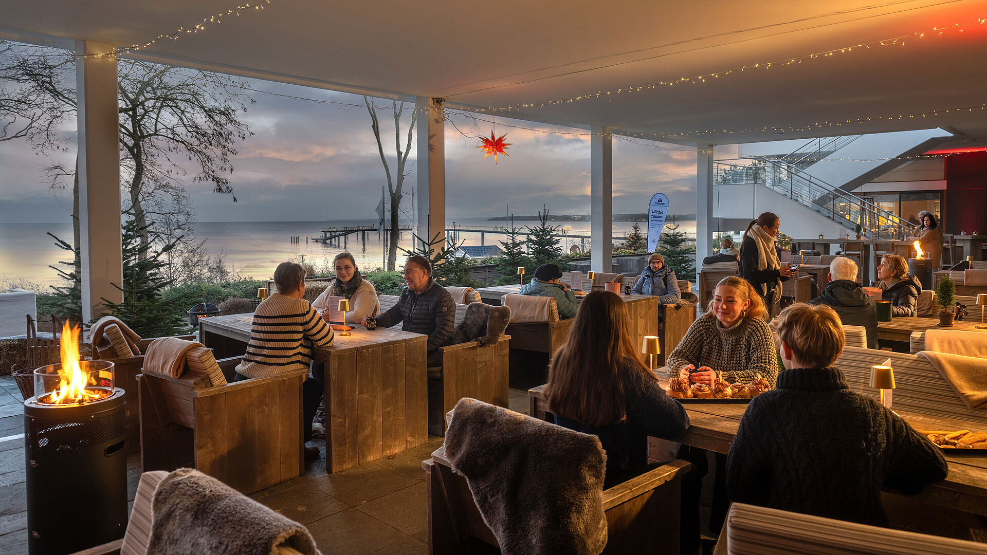 Festlich dekorierter Terrassenbereich mit Kerzenlicht, Winterdekoration und Blick auf die Ostsee.