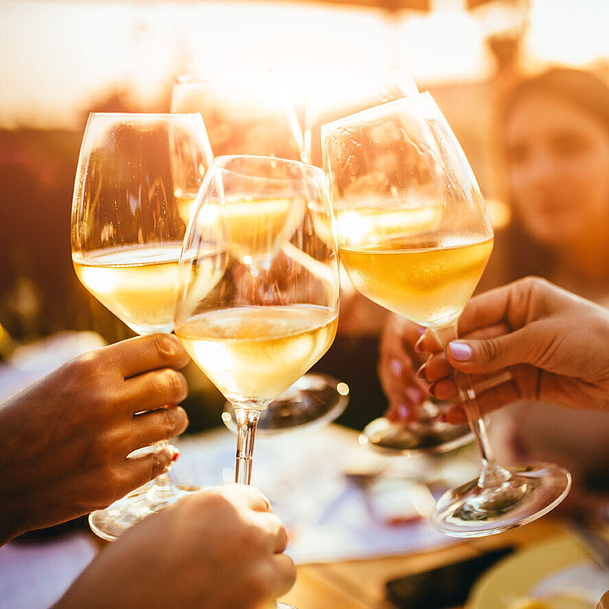 Freunde stoßen mit Weingläsern an und genießen einen gemeinsamen Abend bei Sonnenuntergang
