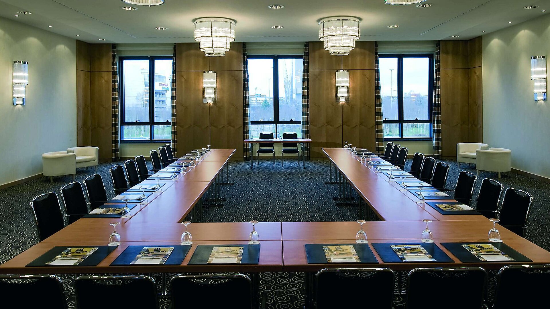 Moderner Konferenzraum im Maritim Hotel Düsseldorf mit U-förmiger Bestuhlung, großen Fenstern und eleganter Beleuchtung.