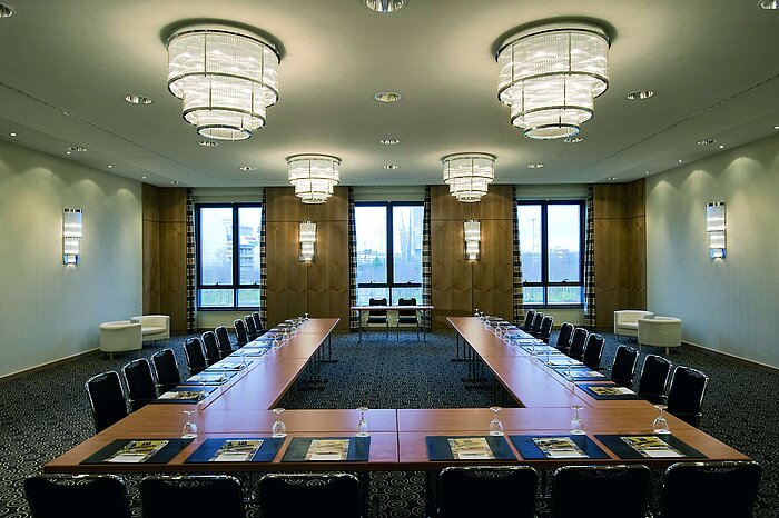 Moderner Konferenzraum im Maritim Hotel Düsseldorf mit U-förmiger Bestuhlung, großen Fenstern und eleganter Beleuchtung.