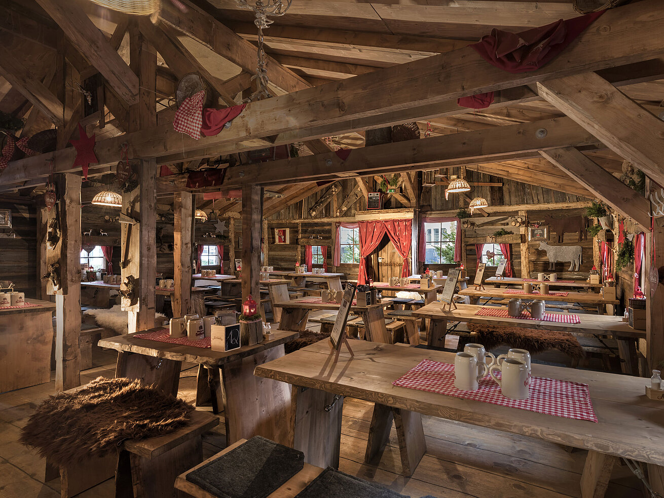 Warmer Innenbereich mit Holztischen, roten Vorhängen und uriger Deko in der Maritim Alm Stuttgart