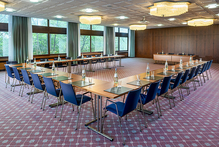U-förmig bestuhlter Tagungsraum mit Teppichboden, großen Fenstern und Blick ins Grüne im Maritim Hotel Travemünde