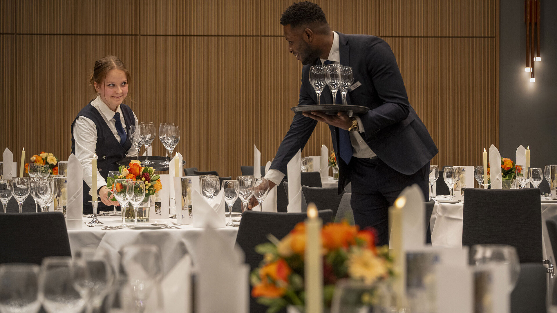 Servicepersonal bei der Tischvorbereitung im Saal Barbarossa Servicepersonal deckt Tische im Saal Barbarossa des Maritim Hotel Würzburg mit Blumenschmuck und Gläsern ein.