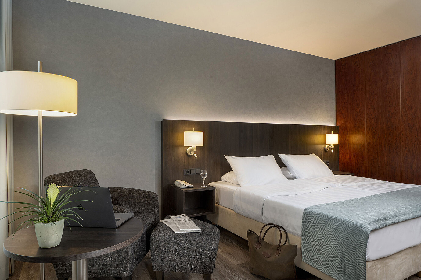 Modernes Doppelzimmer im Maritim Hotel Bremen mit gemütlicher Sitzecke, Beistelltisch, Vase und einladendem Bett.