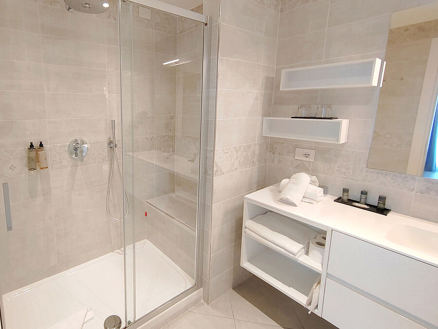 Großes Bad im Maritim Resort Calabria mit Regendusche, weißen Möbeln und viel Platz
