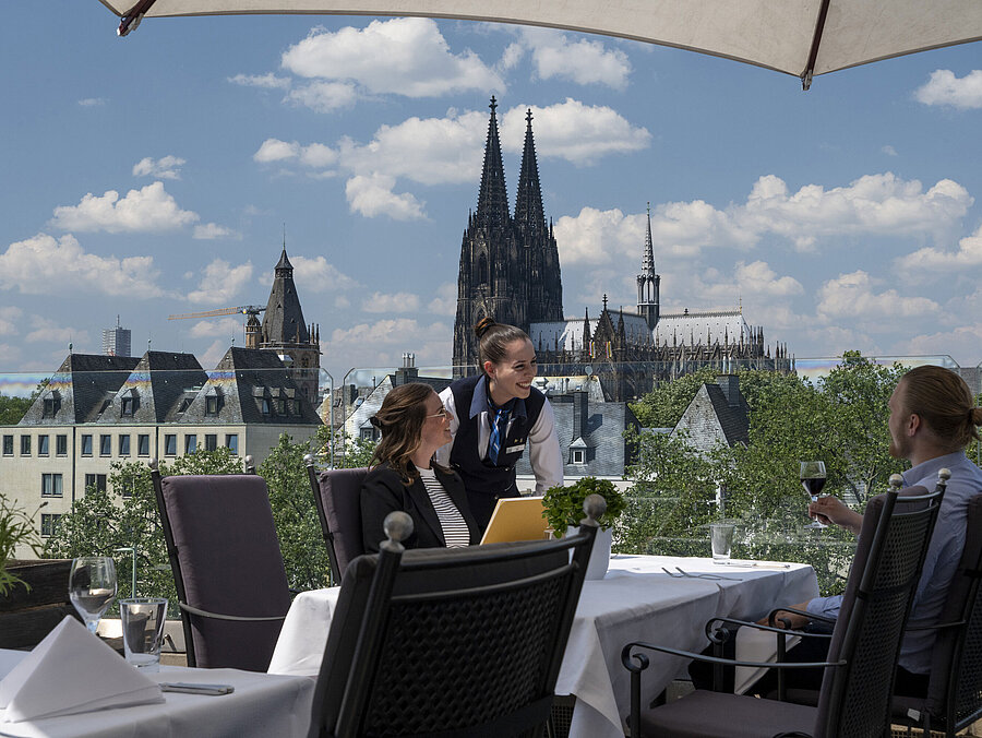 Gäste genießen den Service auf der Dachterrasse des Maritim Hotels Köln mit Blick auf den Kölner Dom und die Altstadt.