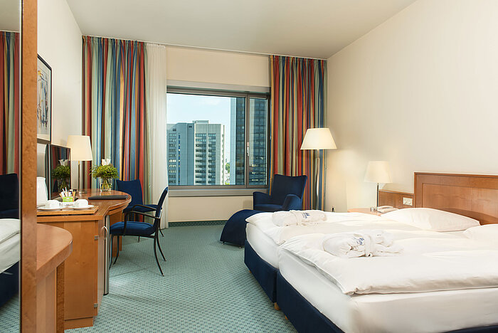 Superior Zimmer im Maritim Hotel Frankfurt mit Doppelbett, Schreibtisch, Sitzbereich und Blick auf die Skyline.