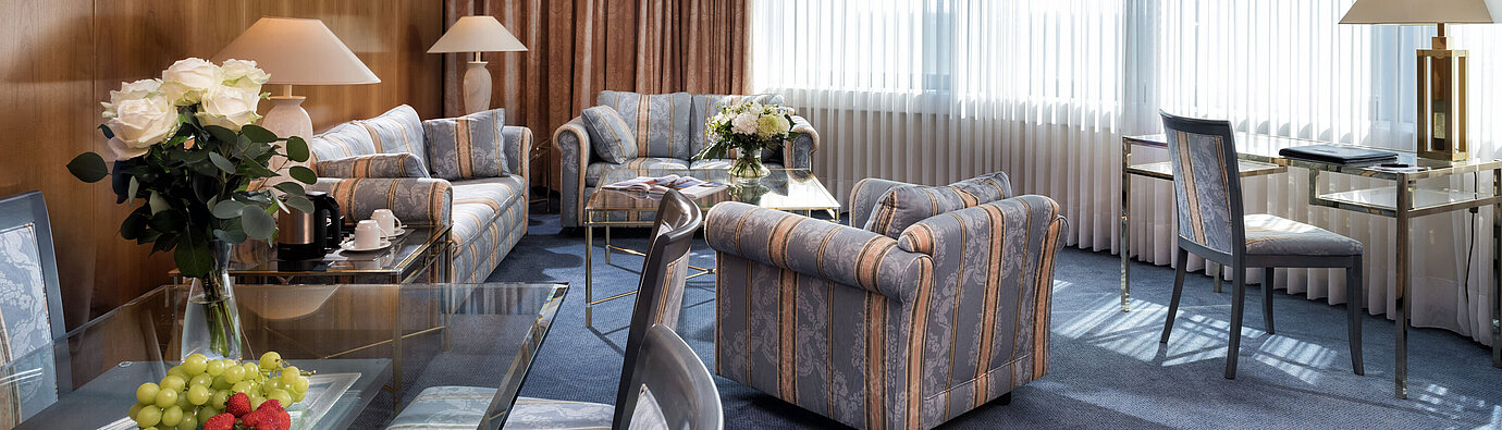 Elegante Master Suite im Maritim Hotel Hannover mit klassischem Design, stilvollen Sitzmöbeln und hellem Panoramafenster.