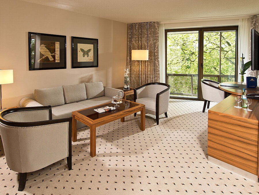 Gemütlicher Wohnbereich der Suite im Maritim Hotel Bad Homburg mit eleganter Sitzecke und Balkon.