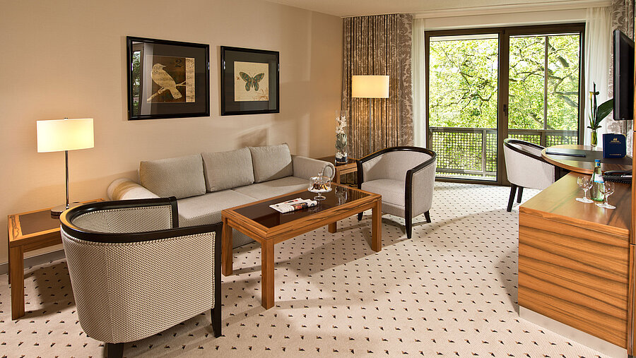 Gemütlicher Wohnbereich der Suite im Maritim Hotel Bad Homburg mit eleganter Sitzecke und Balkon.