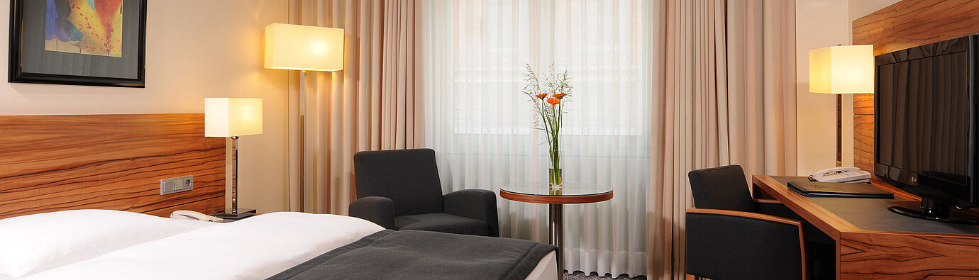 Modernes Einzelzimmer mit Bett, Sesseln und großem Fenster im Maritim Hotel München