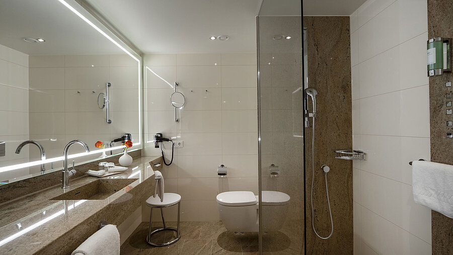 Modernes Badezimmer im Maritim Hotel Ingolstadt mit Glasdusche, großem Spiegel und stilvollem Design.