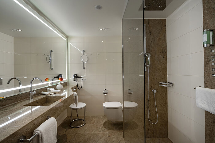 Modernes Badezimmer im Maritim Hotel Ingolstadt mit Glasdusche, großem Spiegel und stilvollem Design.
