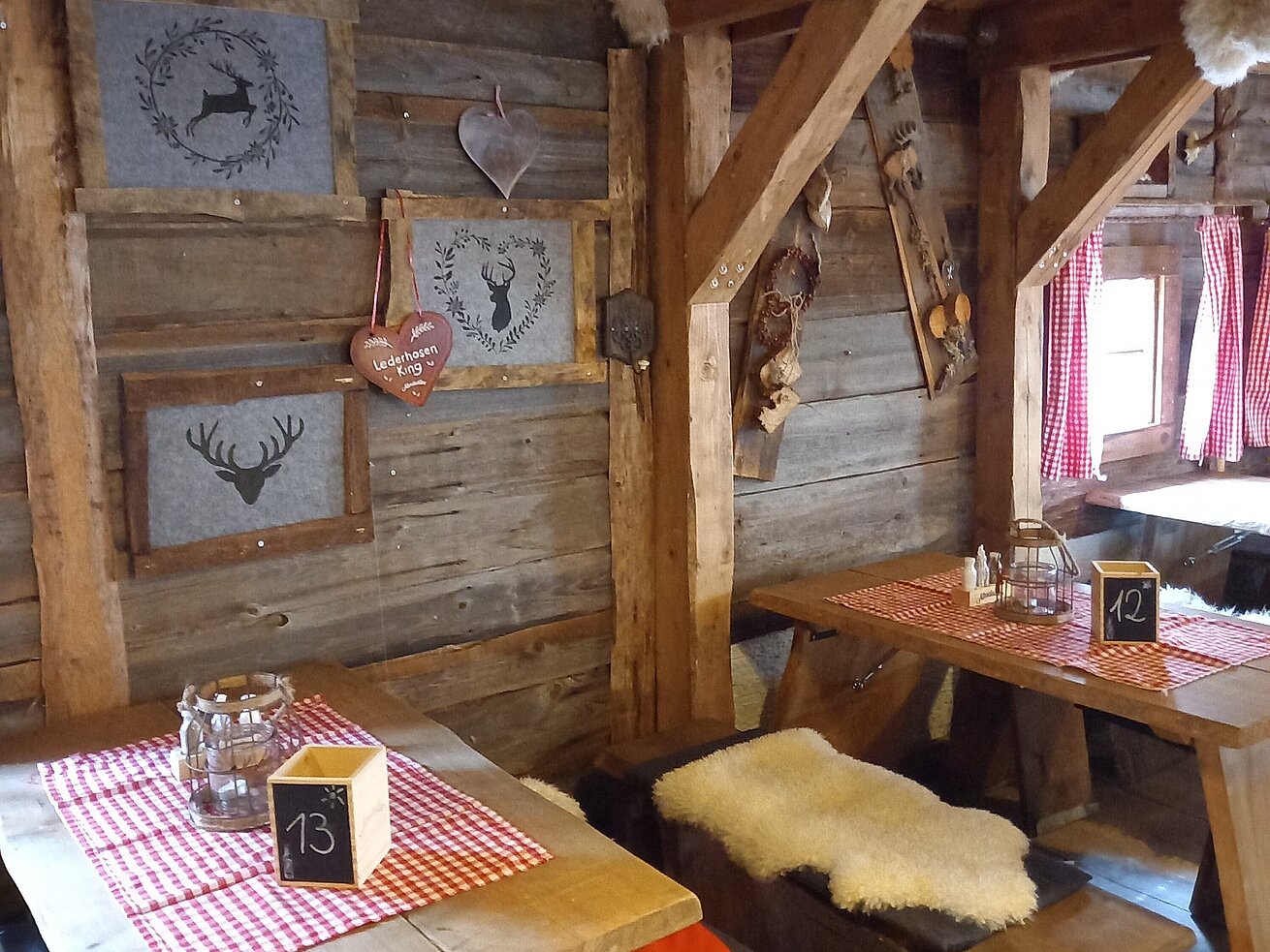 Holzverkleidete Wand mit Hirschmotiven, Herzdeko und rustikalen Sitzplätzen in der Maritim Alm Stuttgart